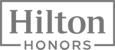 The image displays the logo for Hilton Honors, featuring the brand name in a modern, prominent font placed within a rectangular frame.