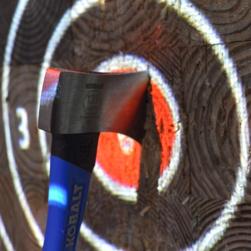 An axe embedded in the center of a target on a wooden surface, showing a successful throw.