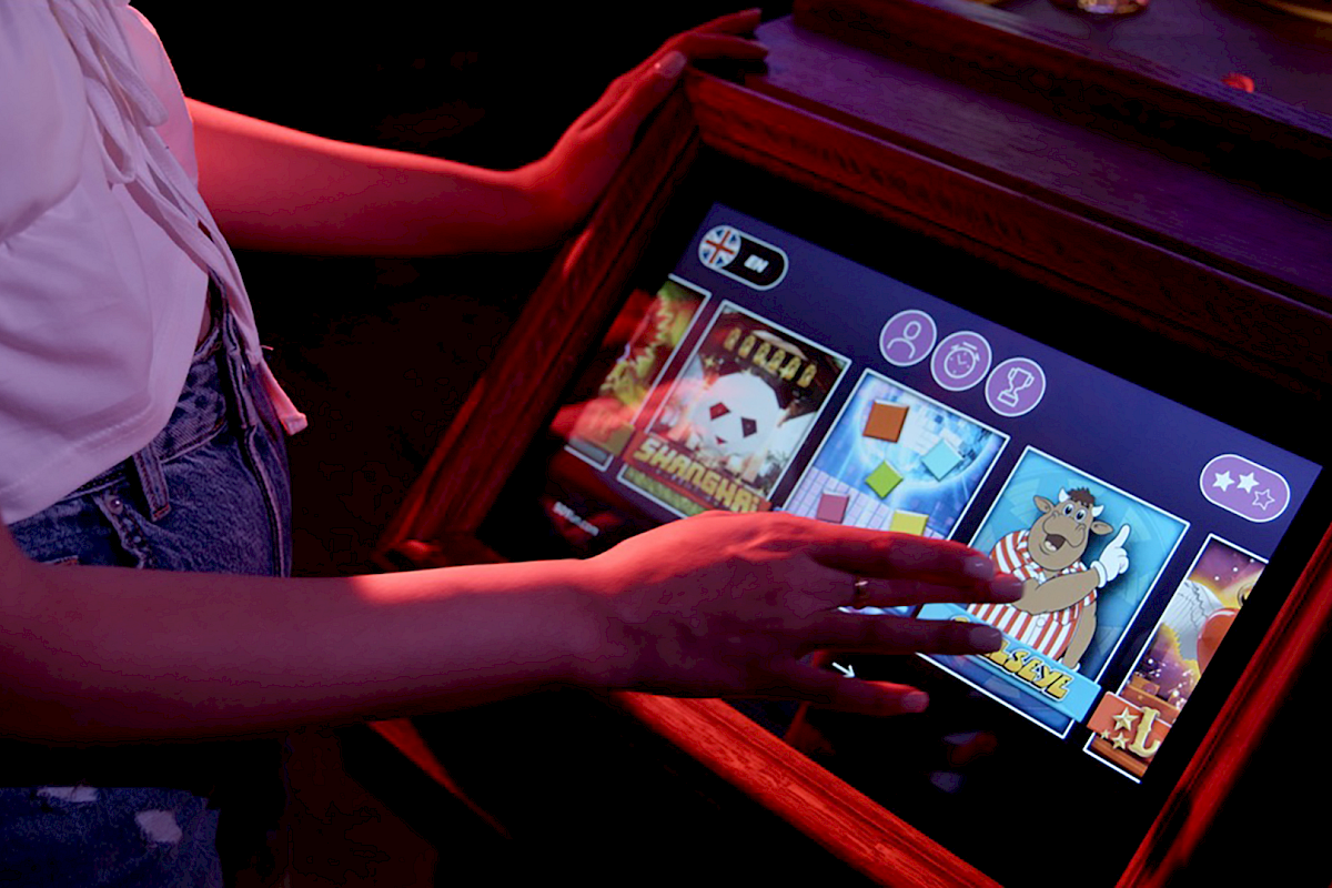 A person is using a touchscreen slot machine with various symbols and games displayed.