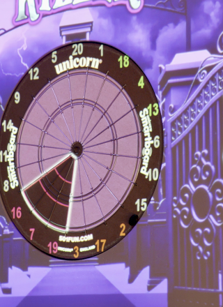 The image shows a digital dartboard game with scores for players, set against a spooky-themed background with character names.