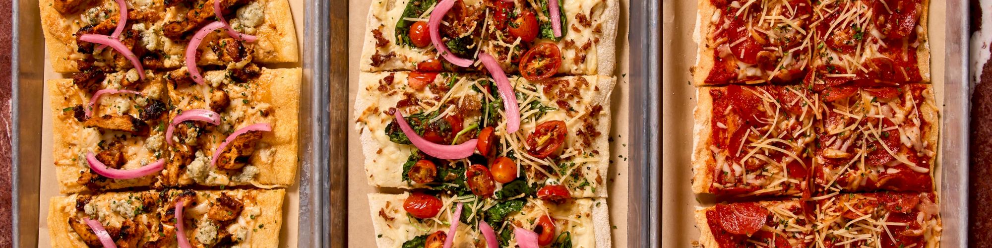 Three pizzas on baking trays with toppings: left looks like mushrooms and onions, middle has greens and peppers, right appears pepperoni with cheese. But the prompt asks to end the sentence with a period and 140 chars max. Ensure 140 chars and ends with a period.