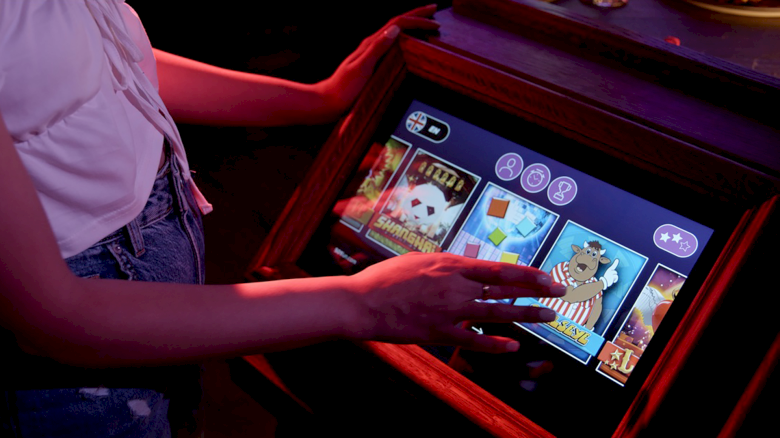 A person is using a touchscreen slot machine with various symbols and games displayed.