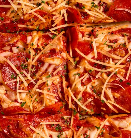 A pepperoni pizza topped with shredded cheese, herbs, and thin slices of pepperoni, baked to bubbling perfection.