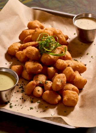 A plate of fried, bite-sized snacks with dipping sauce on the side, likely appetizers or fritters.